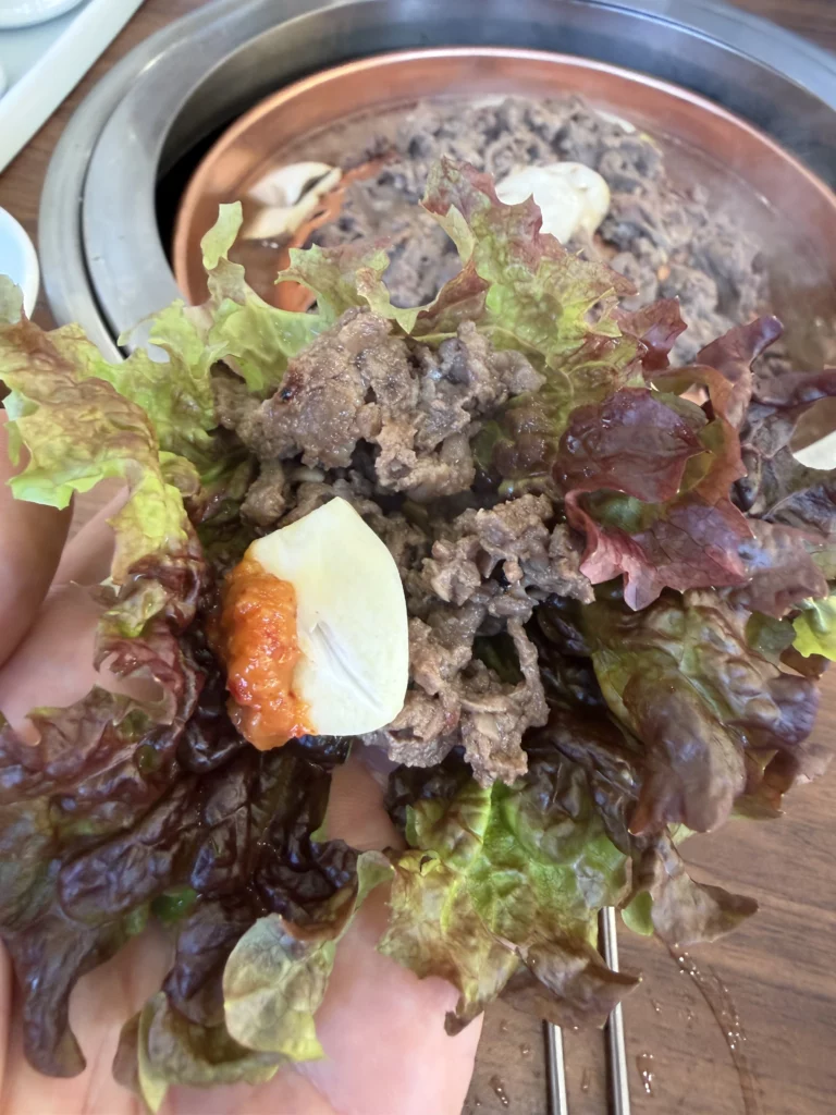 Korean ssam lettuce wrap filled with grilled Hanwoo beef bulgogi, boiled egg, and ssamjang sauce at Woo Lae Oak Seoul, demonstrating traditional Korean BBQ dining culture with fresh vegetables and premium marinated beef.