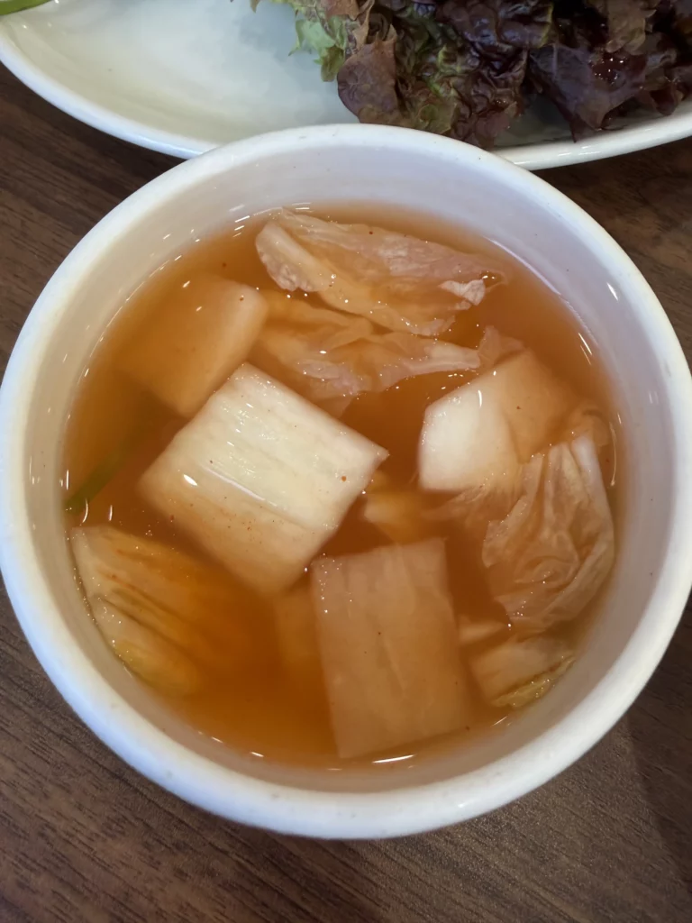 Dongchimi water radish kimchi with fermented radishes in crystal-clear brine, a crucial ingredient for Woo Lae Oak's traditional Pyongyang mul naengmyeon broth providing subtle tangy sweetness and probiotics to the signature cold noodle dish.