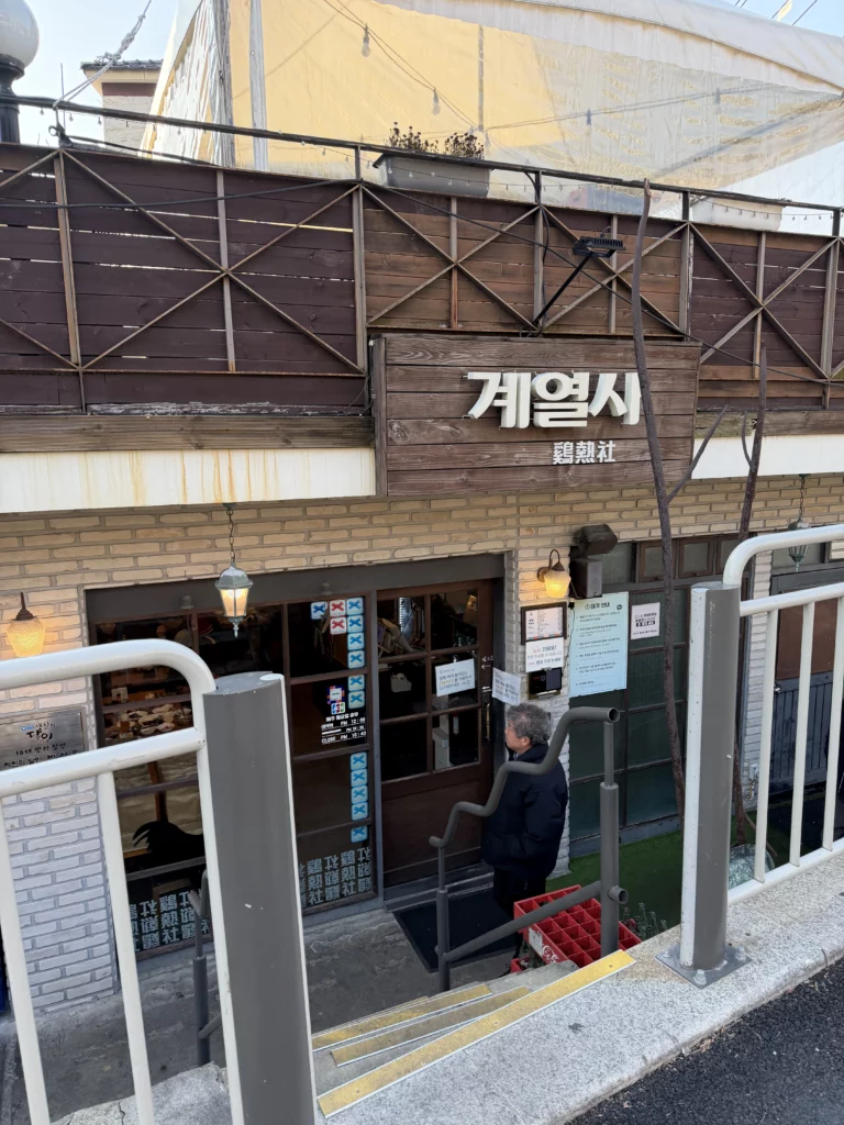 Gyeyeolsa Korean fried chicken restaurant entrance in Buam-dong Seoul with traditional wooden sign and basement stairs near Bugaksan Mountain.