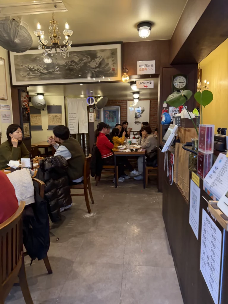 Gyeyeolsa basement dining room with traditional Korean art and customers enjoying chimaek at Seoul Buam-dong fried chicken restaurant.