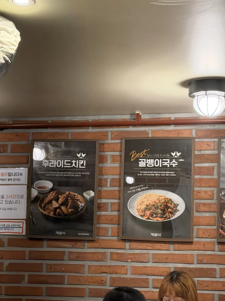 Gyeyeolsa menu posters displaying signature fried chicken and golbaengi noodles at Seoul Buam-dong Korean restaurant.