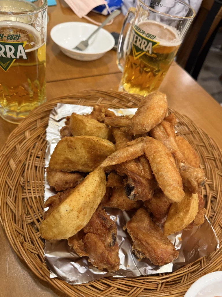 Crispy Korean fried chicken and golden potato wedges served with beer at Gyeyeolsa restaurant in Seoul Buam-dong.
