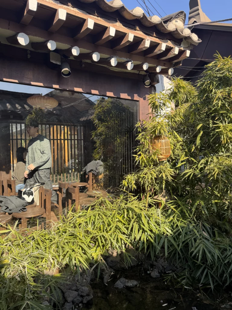 Outdoor seating area at Cheongsu-dang Bakery with traditional hanok wooden architecture, curved roof tiles, and bamboo garden at this historic Ikseon-dong Seoul cafe.