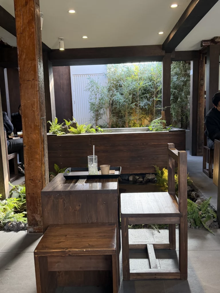 Traditional wooden seating area at Cheongsu-dang Bakery with bamboo garden views and hanok architectural elements, featuring exposed wooden beams and moss-filled planters at this Seoul Ikseon-dong cafe.