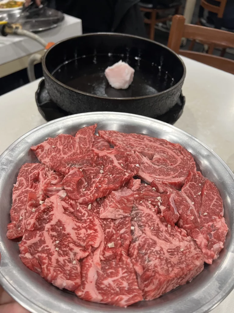 Premium raw Hanwoo beef with exceptional marbling on a metal plate at Woo Lae Oak Seoul, showcasing Korea's prized native cattle breed used for the restaurant's signature tableside-grilled bulgogi specialty.