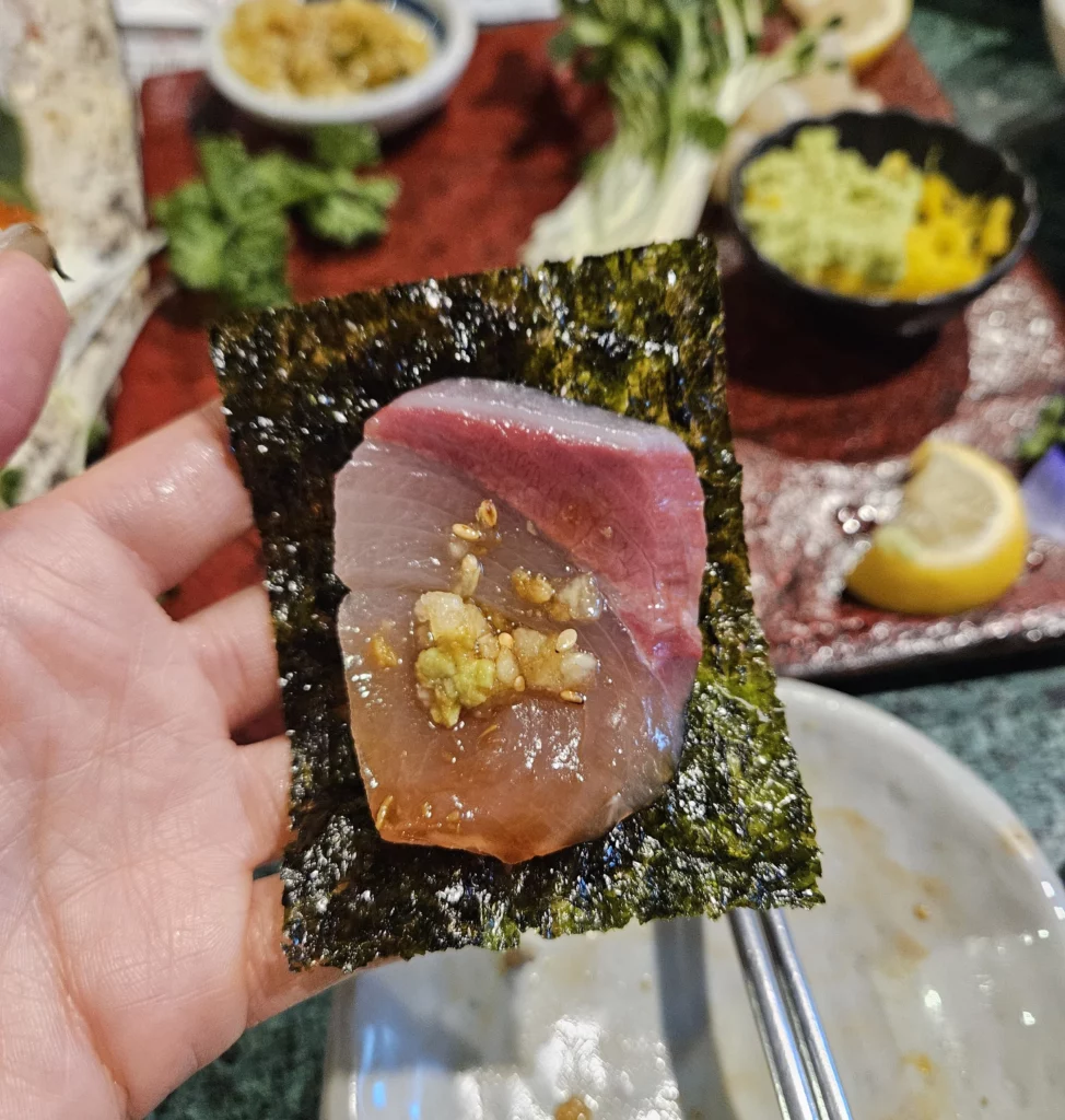 Korean style sashimi seafood in Yongsan wrapped in seasoned seaweed with fresh raw fish and garlic sauce for a traditional bite.