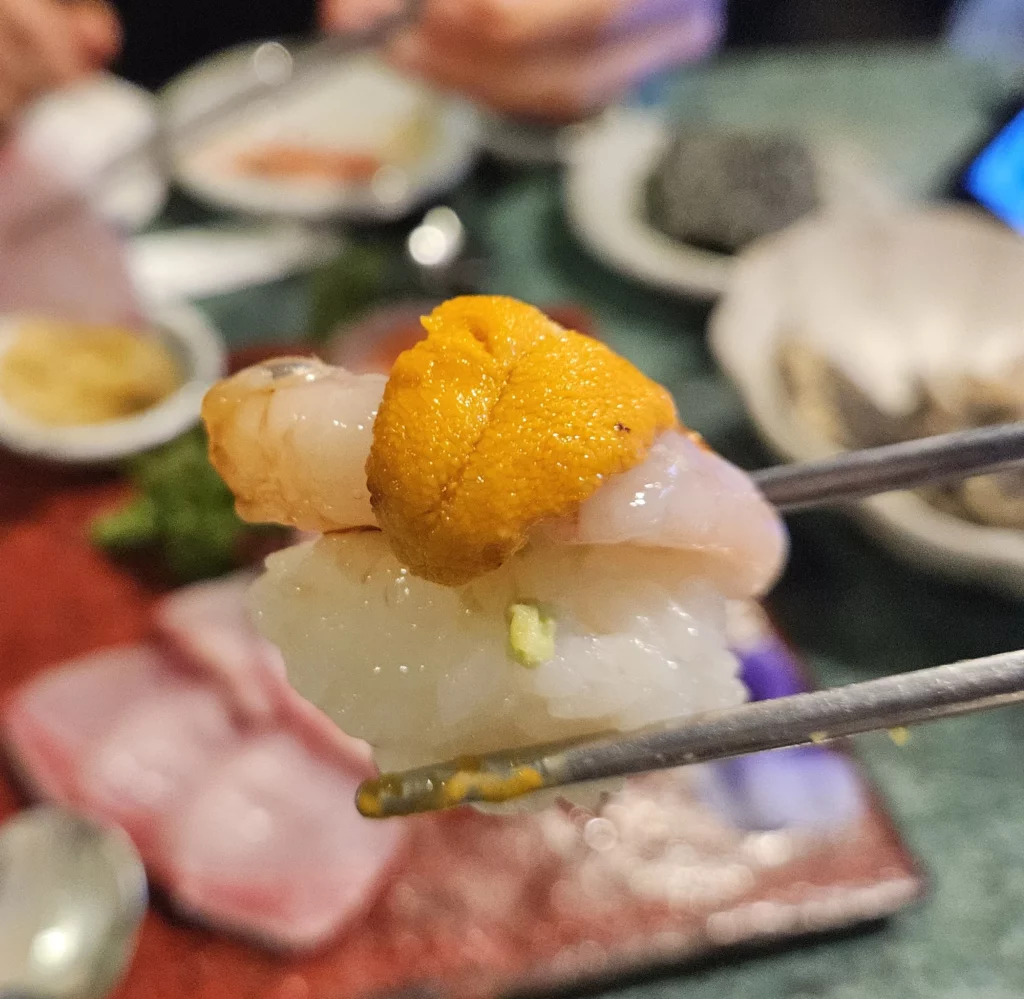 Korean style sashimi seafood in Yongsan featuring shrimp and uni on a bite-sized piece, highlighting premium seafood quality.
