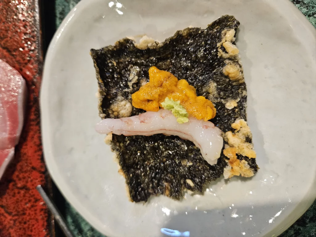 Korean style sashimi seafood in Yongsan served on crispy seaweed with fresh shrimp, uni, and wasabi for a flavorful bite.