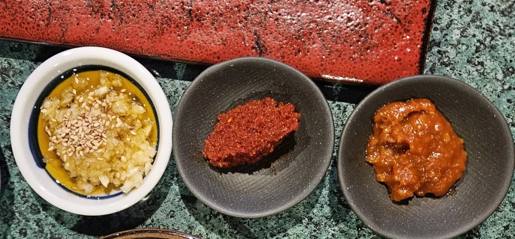 Traditional dipping sauces served with korean styel sashimi seafood in Yongsan, including sesame oil, spicy paste, and seasoned sauce.