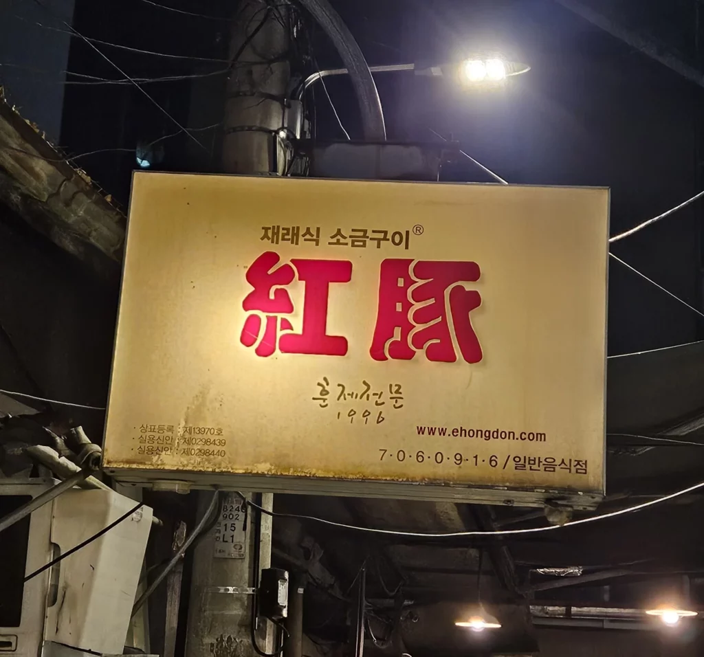 Exterior signboard of a traditional Korean restaurant in Yongsan, known for smoked K-BBQ, featuring vintage signage and a classic local street atmosphere at night.