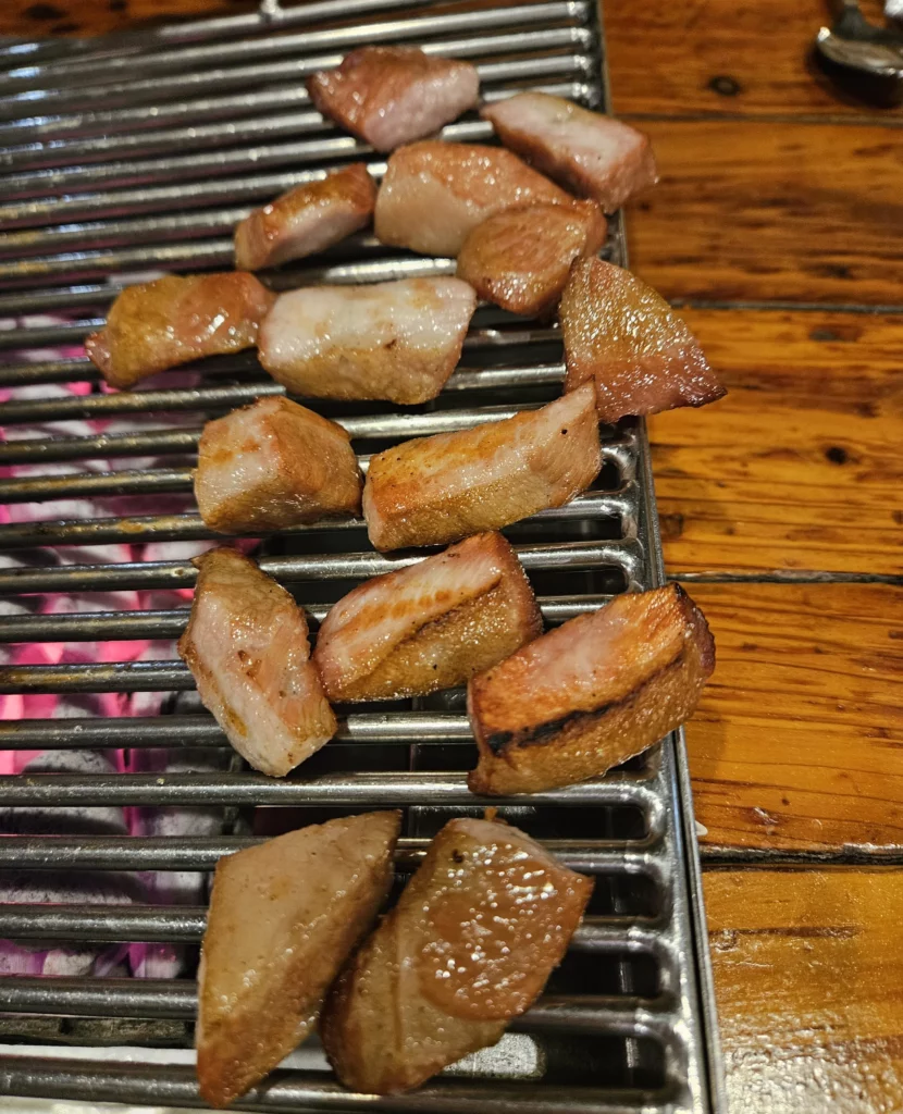 Bite-sized smoked pork cubes grilling over charcoal at a local Yongsan restaurant, showcasing juicy texture and deep smoky flavor typical of authentic smoked K-BBQ.