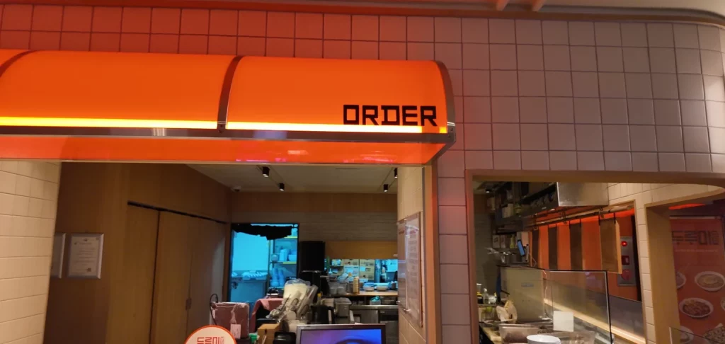 Durumi Bunsik order counter with orange retro-style awning and open kitchen at N Seoul Tower.