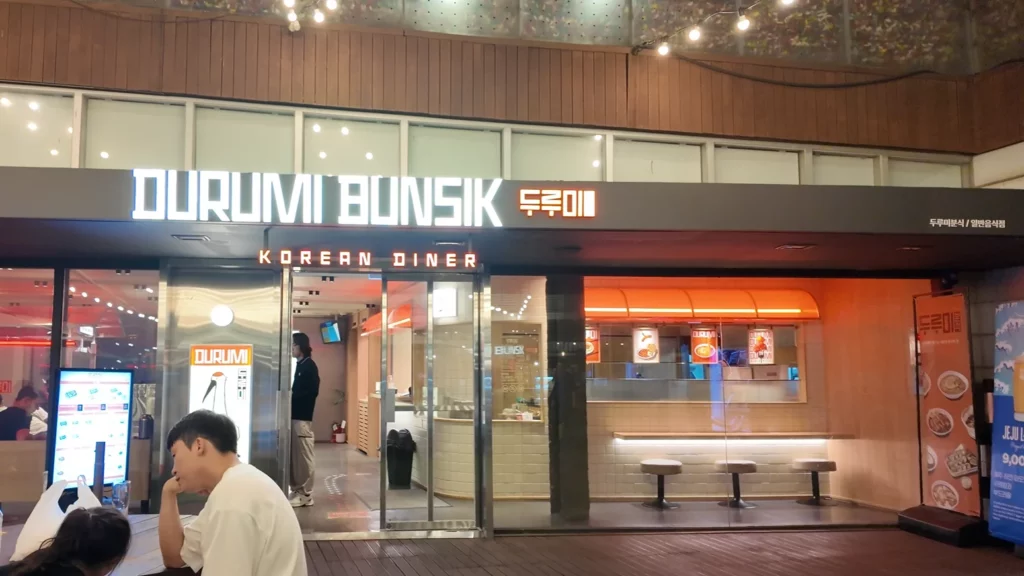 Durumi Bunsik Korean diner storefront entrance at N Seoul Tower plaza with illuminated signage and modern design.