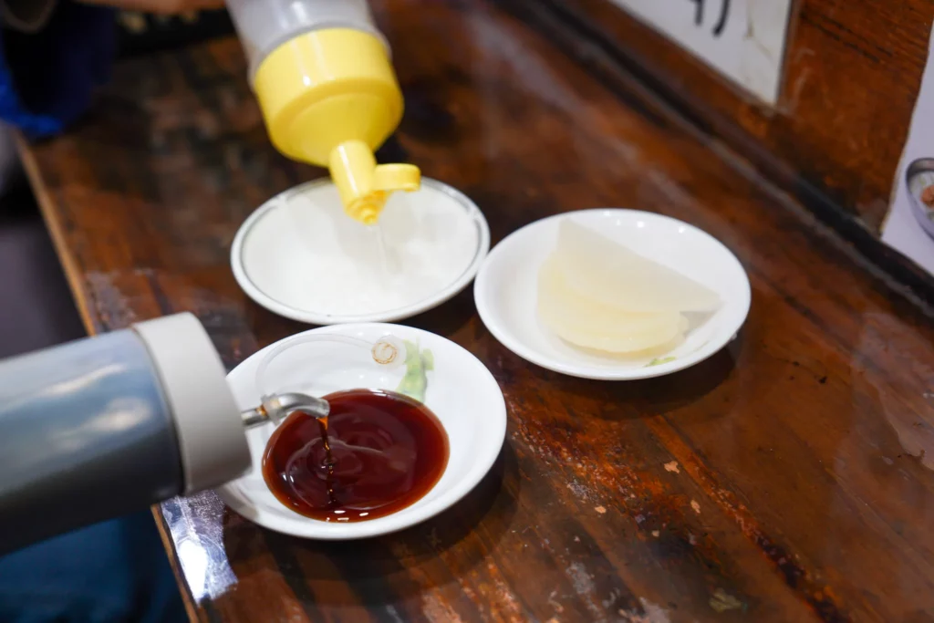 Dipping sauces including soy-vinegar and mustard served alongside pickled radish at Bukchon Son Mandu restaurant.