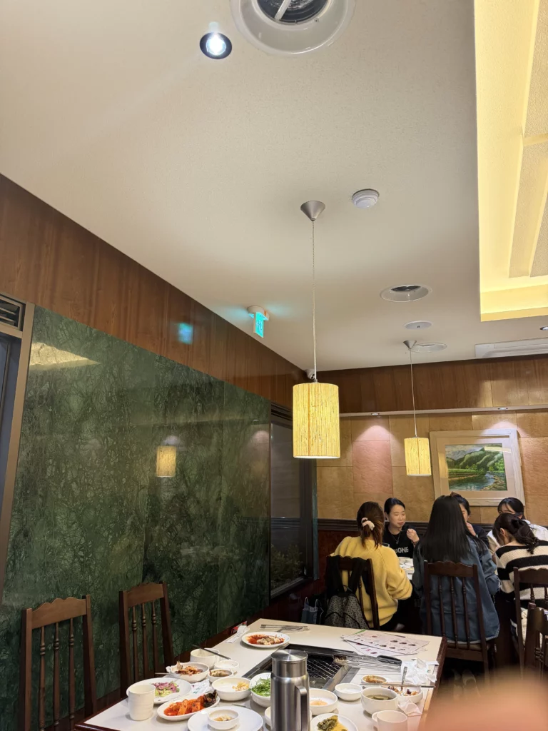 Chowon Korean BBQ restaurant warm interior ambiance with wood paneling and pendant lighting in Gangnam Seoul dining area.