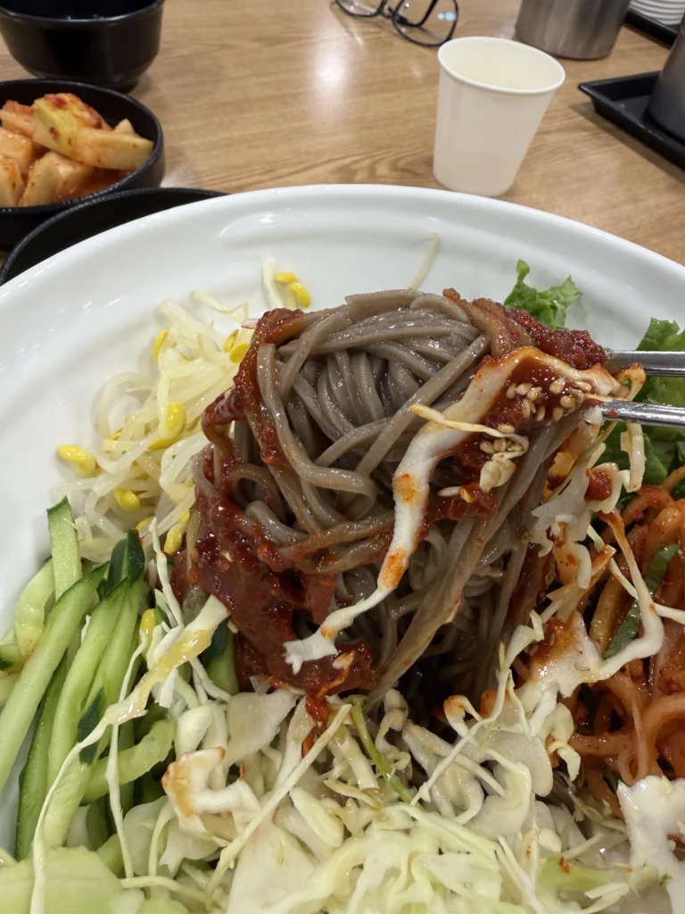 Bibim memil myeon spicy buckwheat noodles with gochujang sauce, julienned vegetables, and soft-boiled egg at Michelin Bib Gourmand Mijin restaurant in Seoul.