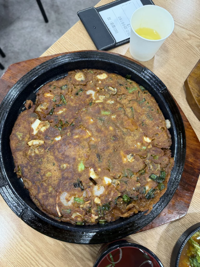 Memil kimchi jeon buckwheat pancake with fermented kimchi served in traditional stone pot at Mijin Michelin-starred Korean restaurant in Seoul.
