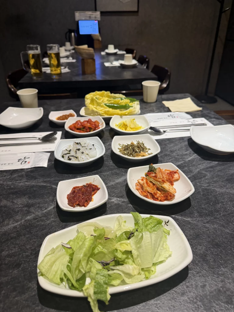 Korean banchan spread for hanjeongsik with kimchi varieties, pickled vegetables, fresh lettuce, and napa cabbage at Dam Restaurant hansangcharim table setting in Seoul Arts Center.