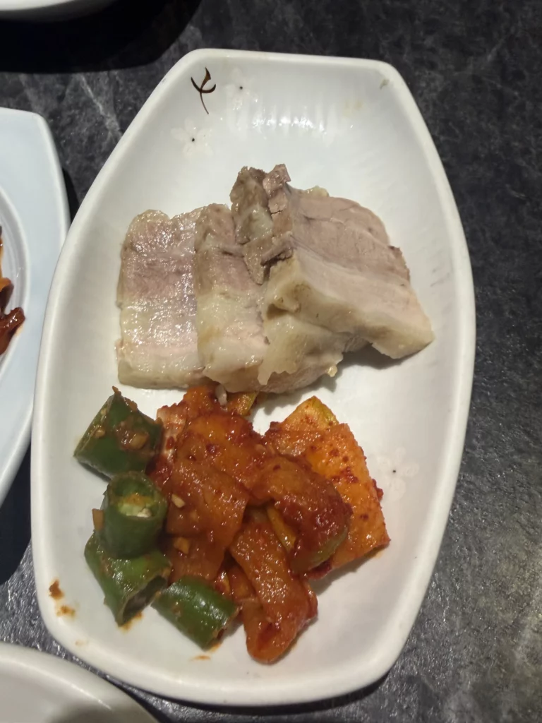 Bossam boiled pork slices with spicy kkakdugi radish kimchi and green pepper, traditional Korean banchan from Dam Restaurant hanjeongsik meal at Seoul Arts Center.