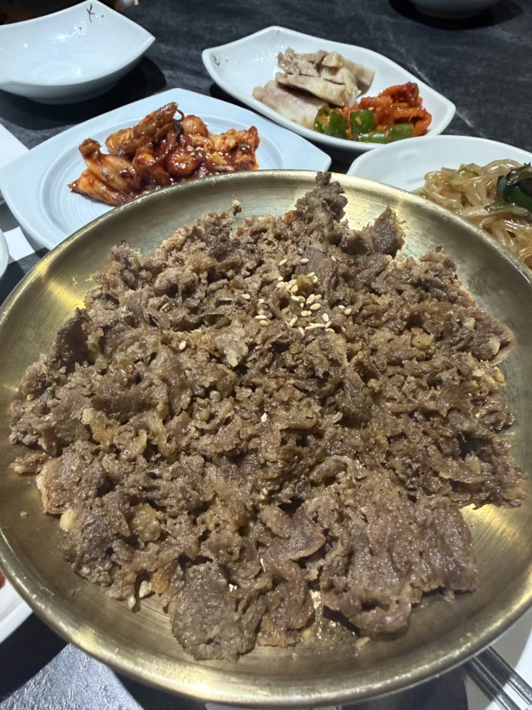 Bulgogi marinated Korean beef with sesame seeds on brass plate, traditional hanjeongsik main dish from Dam Restaurant hansangcharim meal at Seoul Arts Center.