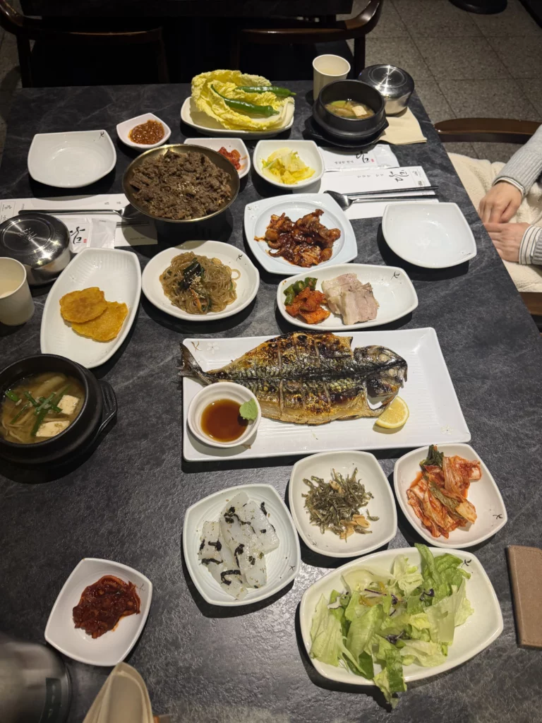 Dam Restaurant hansangcharim hanjeongsik spread featuring grilled mackerel, japchae glass noodles, bossam pork wraps, kimchi banchan, doenjang soup, and traditional Korean side dishes at Seoul Arts Center.