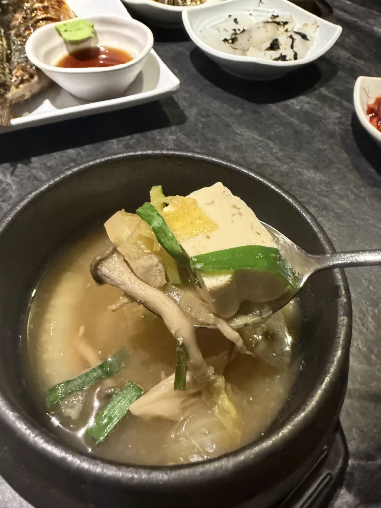 Doenjang guk Korean fermented soybean paste soup with tofu, mushrooms, and green onions in stone bowl, traditional hanjeongsik soup from Dam Restaurant at Seoul Arts Center.