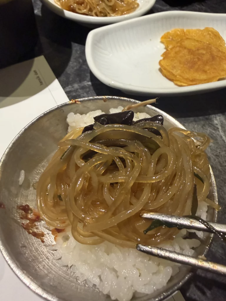 Jjukkumi bibimbap with glass noodles and seaweed over steamed rice being mixed with chopsticks, specialty dish from Dam Restaurant hanjeongsik hansangcharim at Seoul Arts Center.