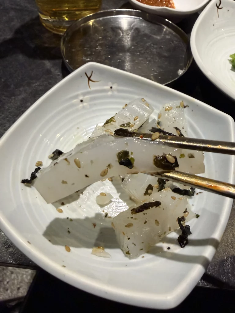 Cubed radish mu with sesame seeds and seaweed banchan held in chopsticks, traditional Korean pickled side dish from Dam Restaurant hanjeongsik meal at Seoul Arts Center.