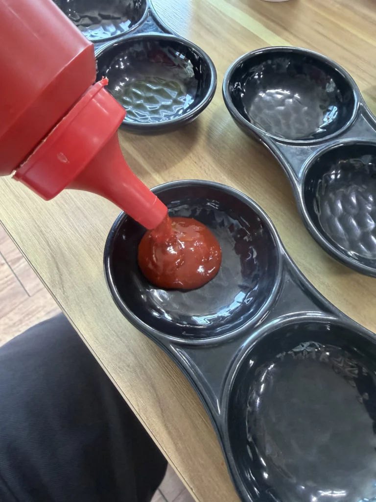 Choganjang (초장) being poured into individual dipping bowls before eating Korean trout sashimi (송어회) — the signature gochujang-vinegar sauce served with freshwater fish at Vivaldi Songeogol.