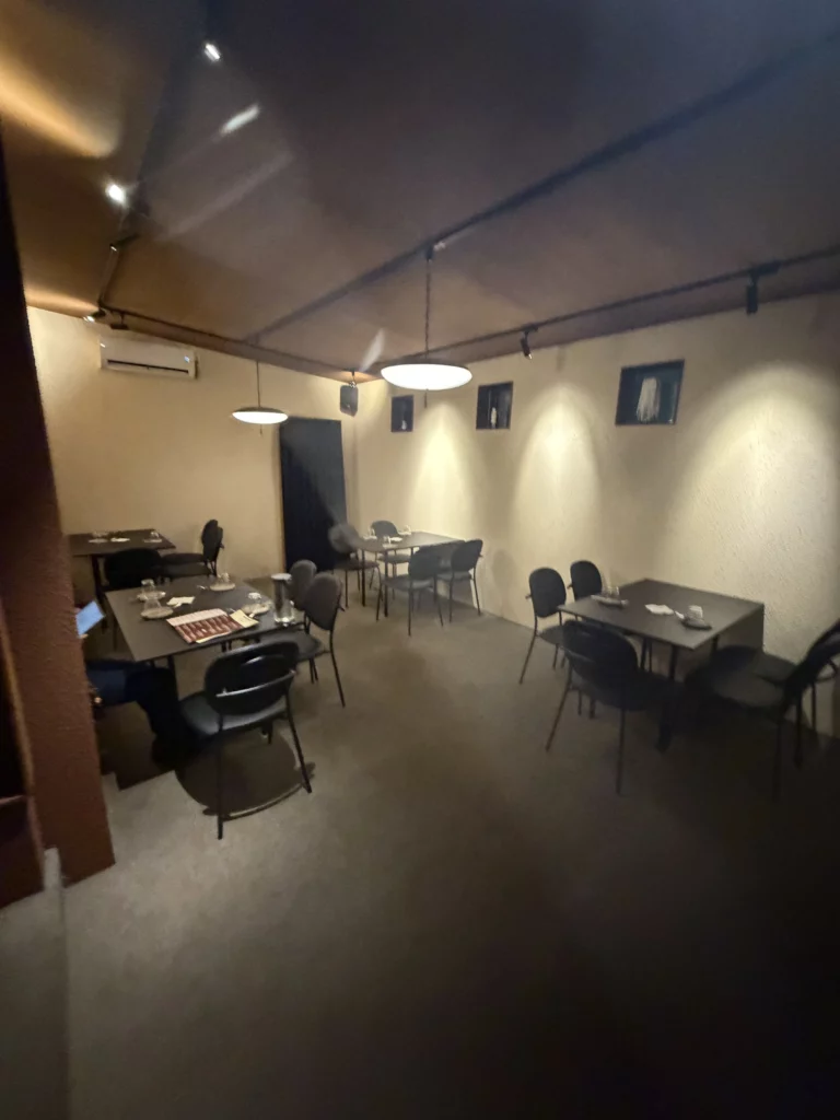 Quiet private dining area at Charari in Sinsa-dong Seoul, with pre-set dark tables, black chairs, warm pendant lighting, and framed wall art, offering an intimate atmosphere for a modern Korean galbi dinner.