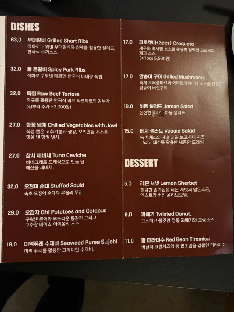 Charari's bilingual Dishes and Dessert menu page, listing signature items including 불등갈비 Spicy Pork Ribs (₩32,000), 미역퓨레 수제비 Seaweed Puree Sujebi (₩19,000), and 항정 냉채 Chilled Vegetables with Jowl (₩27,000), alongside desserts such as 팥 티라무수 Red Bean Tiramisu (₩11,000) at Charari in Sinsa-dong Seoul.