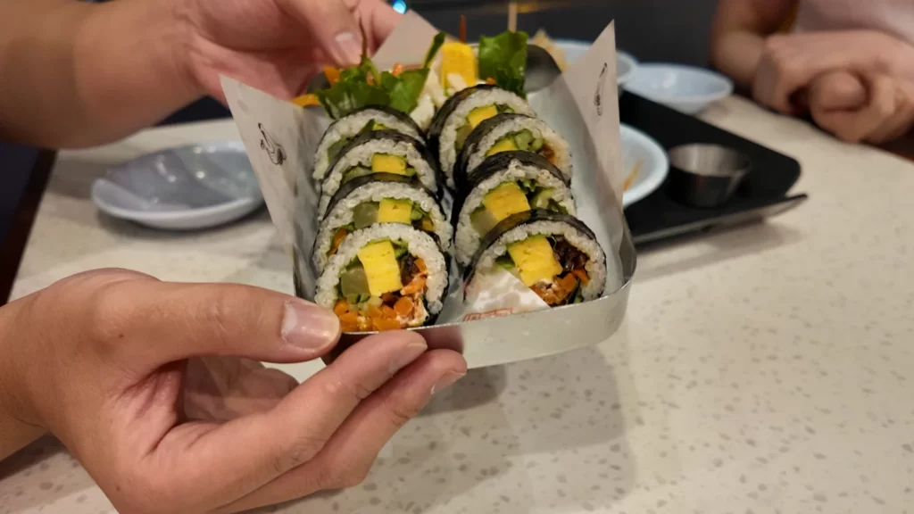 Close-up of freshly made Namsan gimbap from Durumi Bunsik showing colorful vegetable and egg fillings wrapped in roasted seaweed.