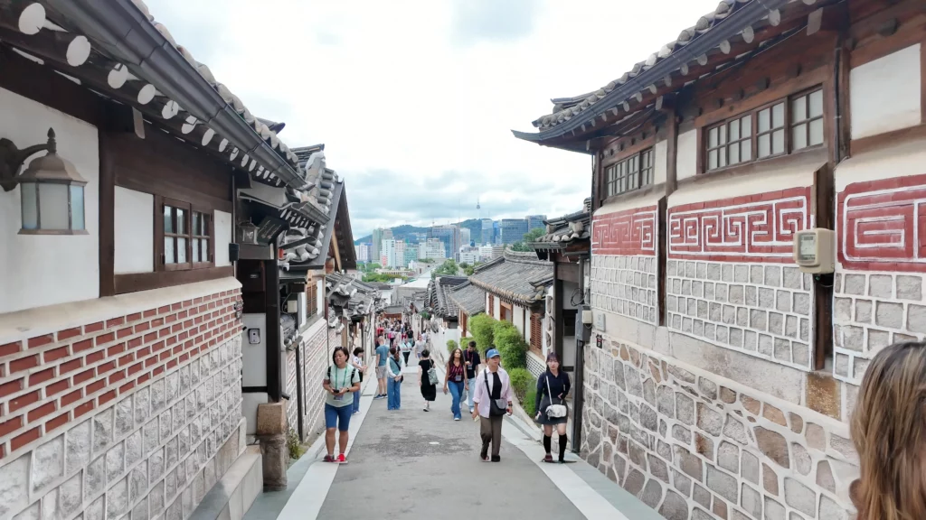 Visitors walking through Bukchon Hanok Village traditional Korean alleyway near Bukchon Son Mandu restaurant in Seoul.
