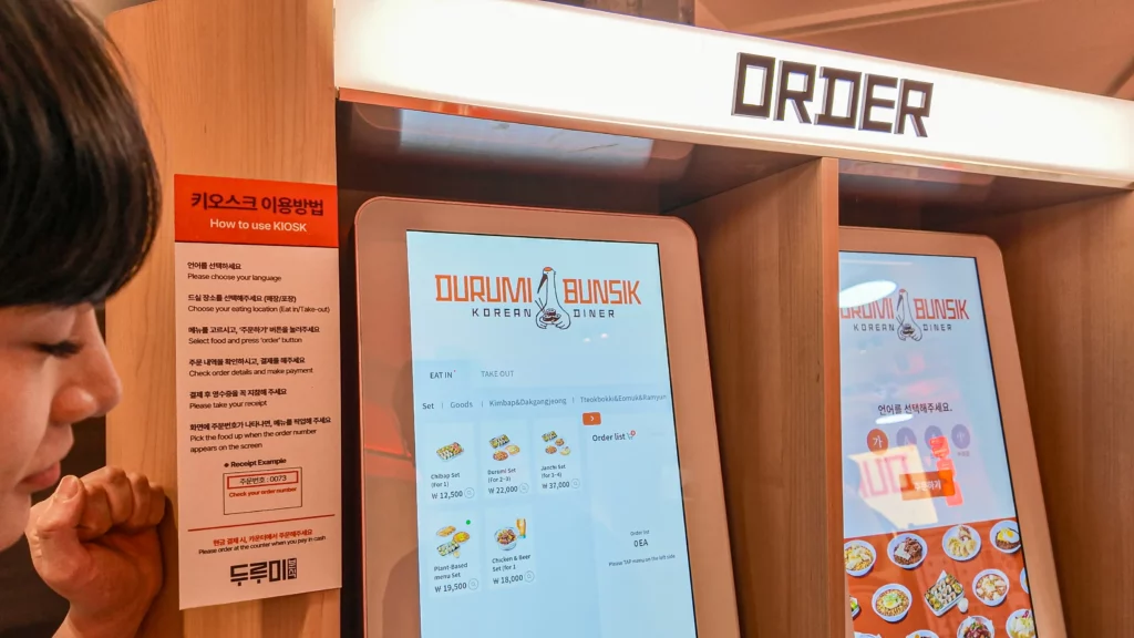 Self-service ordering kiosk at Durumi Bunsik Korean Diner with digital menu display.