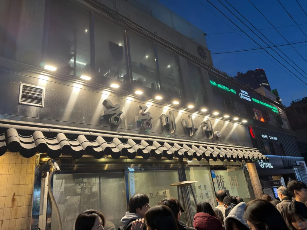 Neungdong Minari famous Korean restaurant exterior with people waiting in line, known for fresh minari dishes and yukhoe in Seoul.