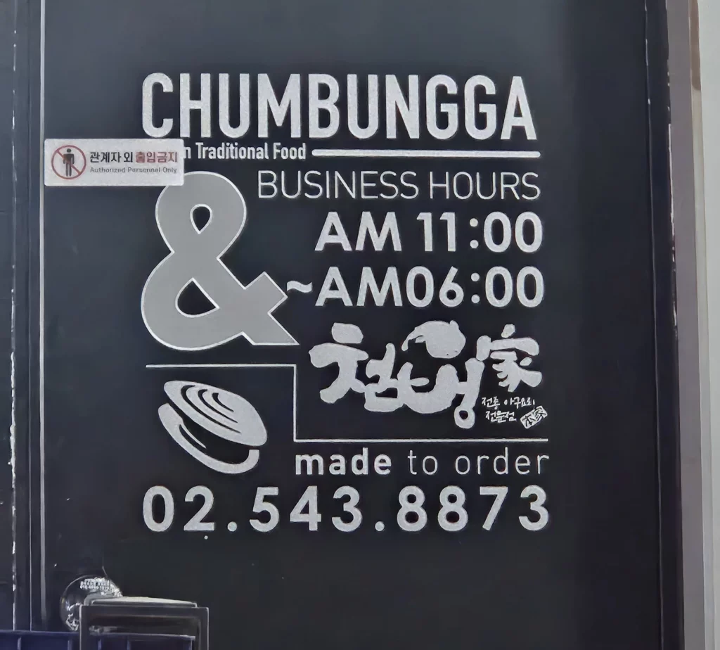 Agujjim: Garosu-gil Braised Monkfish restaurant sign at Chumbungga in Garosu-gil, displaying business hours and Korean traditional seafood restaurant branding on the entrance door.