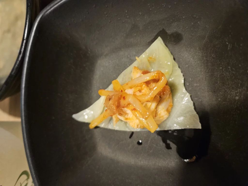 Agujjim: Garosu-gil Braised Monkfish served wrapped in a cabbage leaf with spicy monkfish, bean sprouts, and sauce, a Korean seafood bite at a Garosu-gil restaurant.