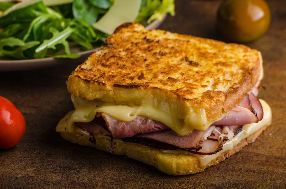 Western-style grilled ham and cheese sandwich with melted cheese, showing the contrast to Korean street toast's sweet-savory approach.