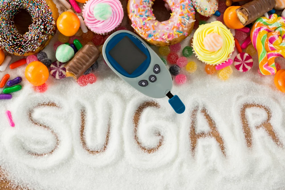 White sugar spelled out on a surface surrounded by sweets, representing the signature sweet element in Korean street toast's danzzhan flavor.

