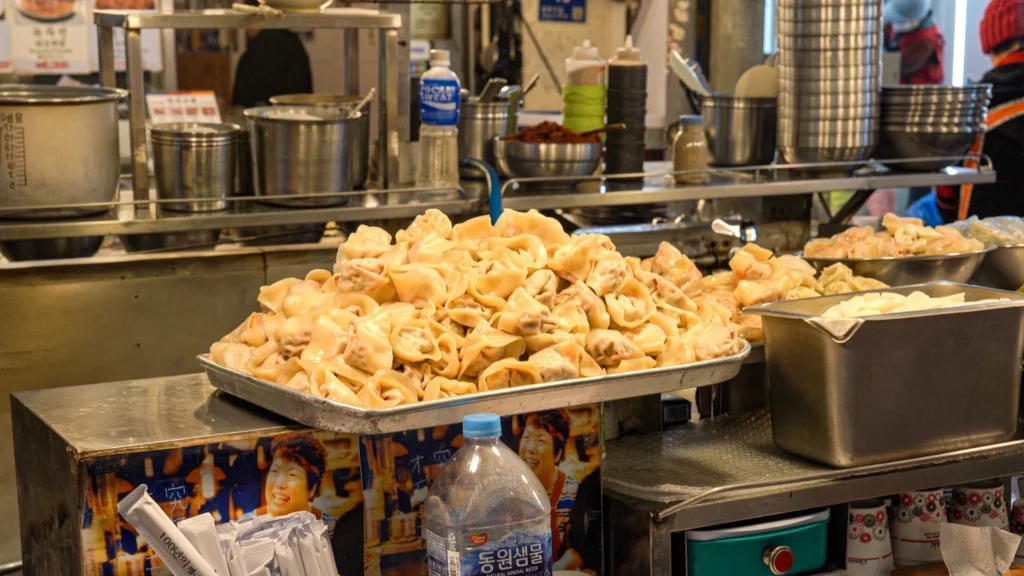 A large tray of freshly hand-made raw mandu dumplings piled high on the counter at Gabose Bibimbap, ready to be cooked to order