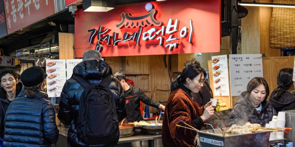 Gangga-ne Tteokbokki stall at Gwangjang Market with customers queuing beneath the red signboard as steam rises from cooking pots.
