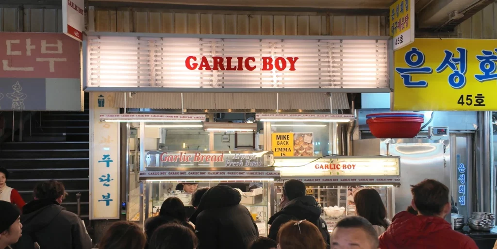 The full exterior facade of Garlic Boy at Gwangjang Market, with the illuminated 