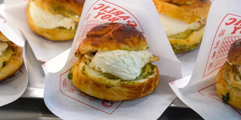 Garlic Boy soft cream garlic bread split open to reveal a generous cream cheese filling, wrapped in branded Garlic Boy paper