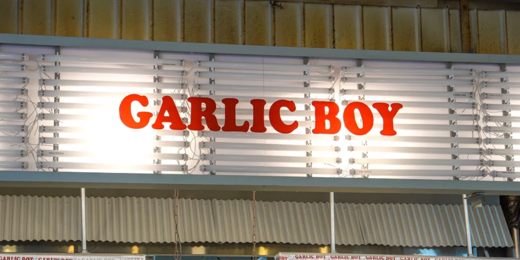 Garlic Boy illuminated storefront sign in bold red letters on a white backlit panel at Gwangjang Market.