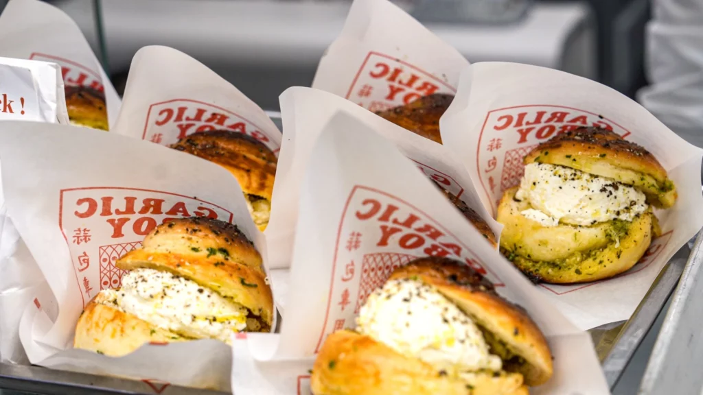 Multiple Garlic Boy truffle cream garlic bread portions wrapped in branded paper and displayed side by side on a serving tray.
