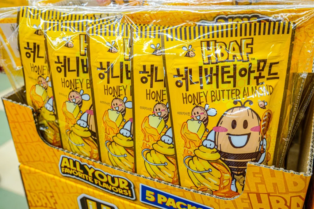 Close-up of HBAF Honey Butter Almond 5-pack bundles with bee mascots inside a cardboard display at the Myeongdong store.
