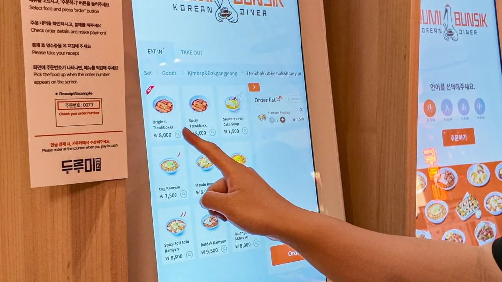Durumi Bunsik self-order kiosk touchscreen showing menu with tteokbokki and ramyun options