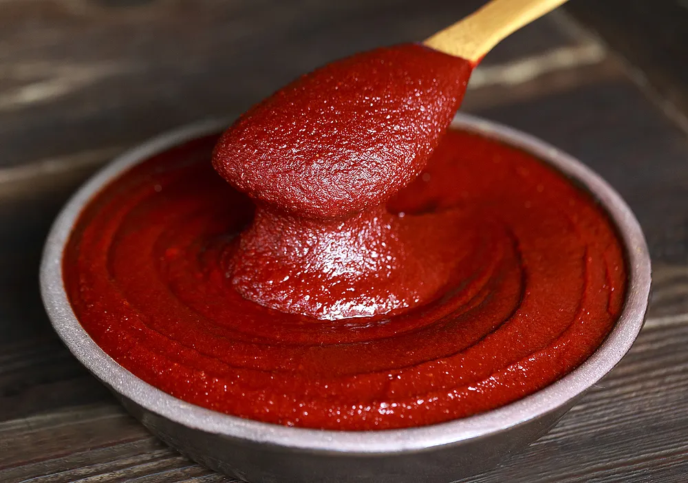 Gochujang red pepper paste in bowl with spoon, key ingredient in Durumi Bunsik tteokbokki sauce