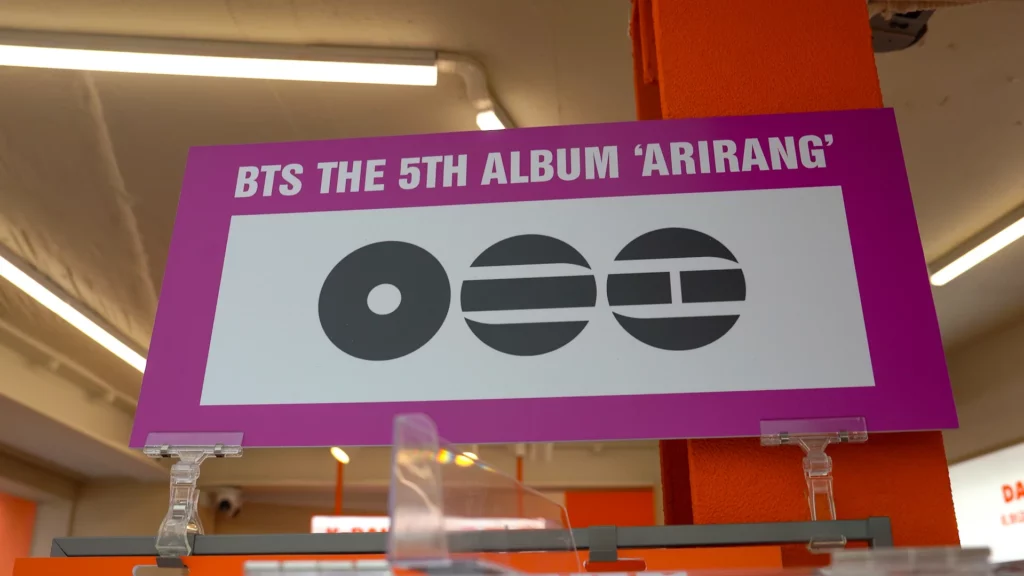 Purple promotional signboard displaying the BTS 5th Album 'Arirang' cover with the stylized circular logo.