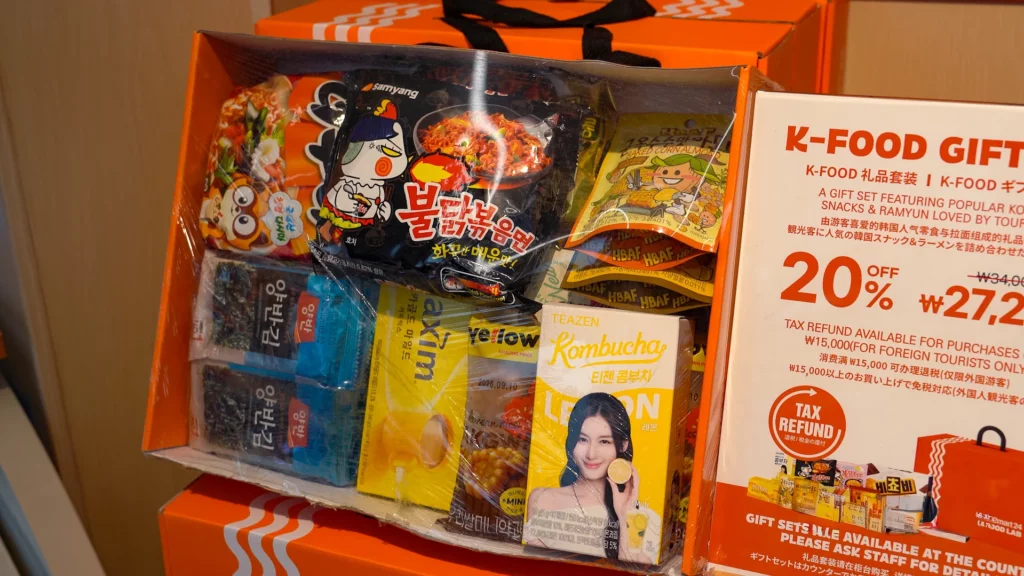Emart24 K-Food Lab Myeongdong K-Food Gift Set featuring Buldak ramen, seaweed, Teazen kombucha, and HBAF almonds at 20% off with tax refund.

